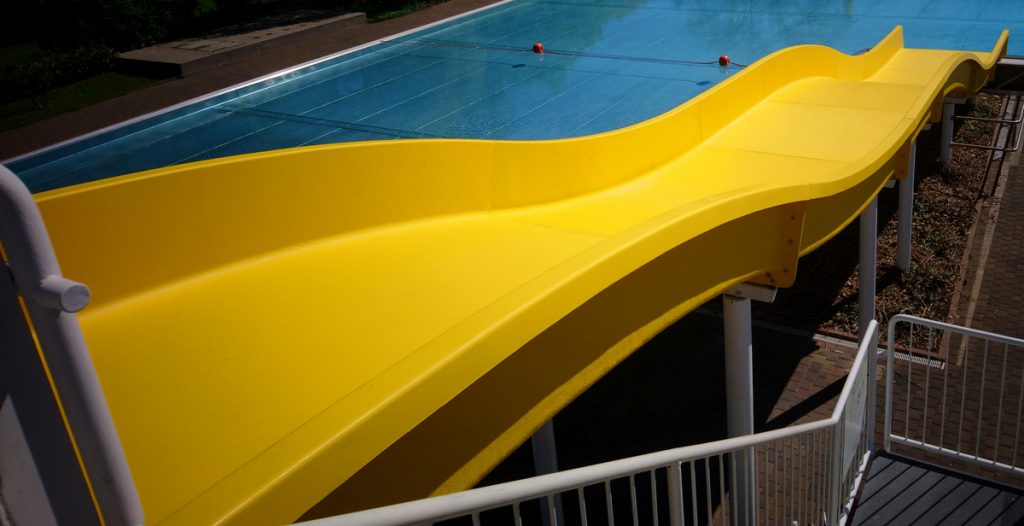 Wasserrutsche von oben fotografiert mit Blick aufs Schwimmbecken